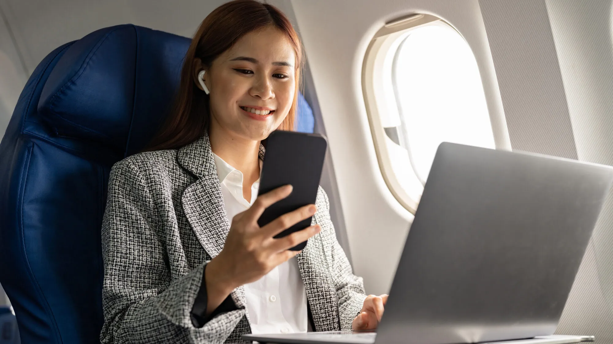 Woman uses mobile and laptop devices on plane